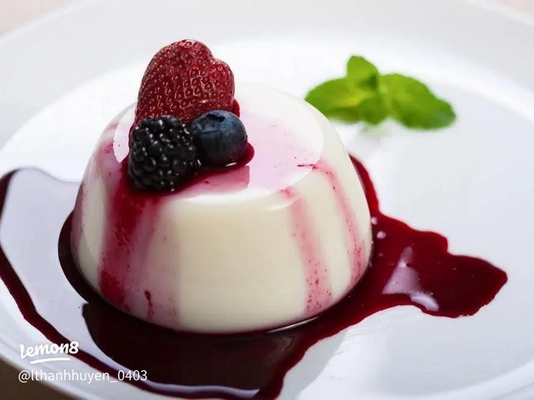Panna cotta rung nhẹ trên đĩa với sốt trái mọng đỏ