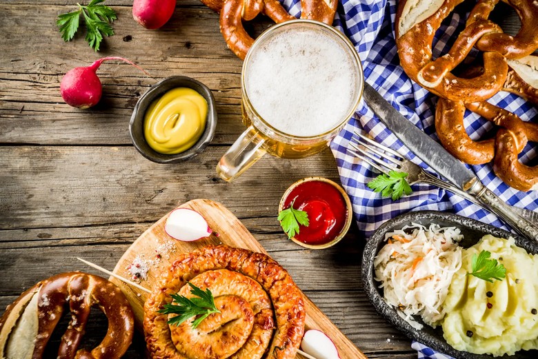 Đĩa xúc xích Bavaria cùng pretzel và một cốc bia lớn trên bàn gỗ